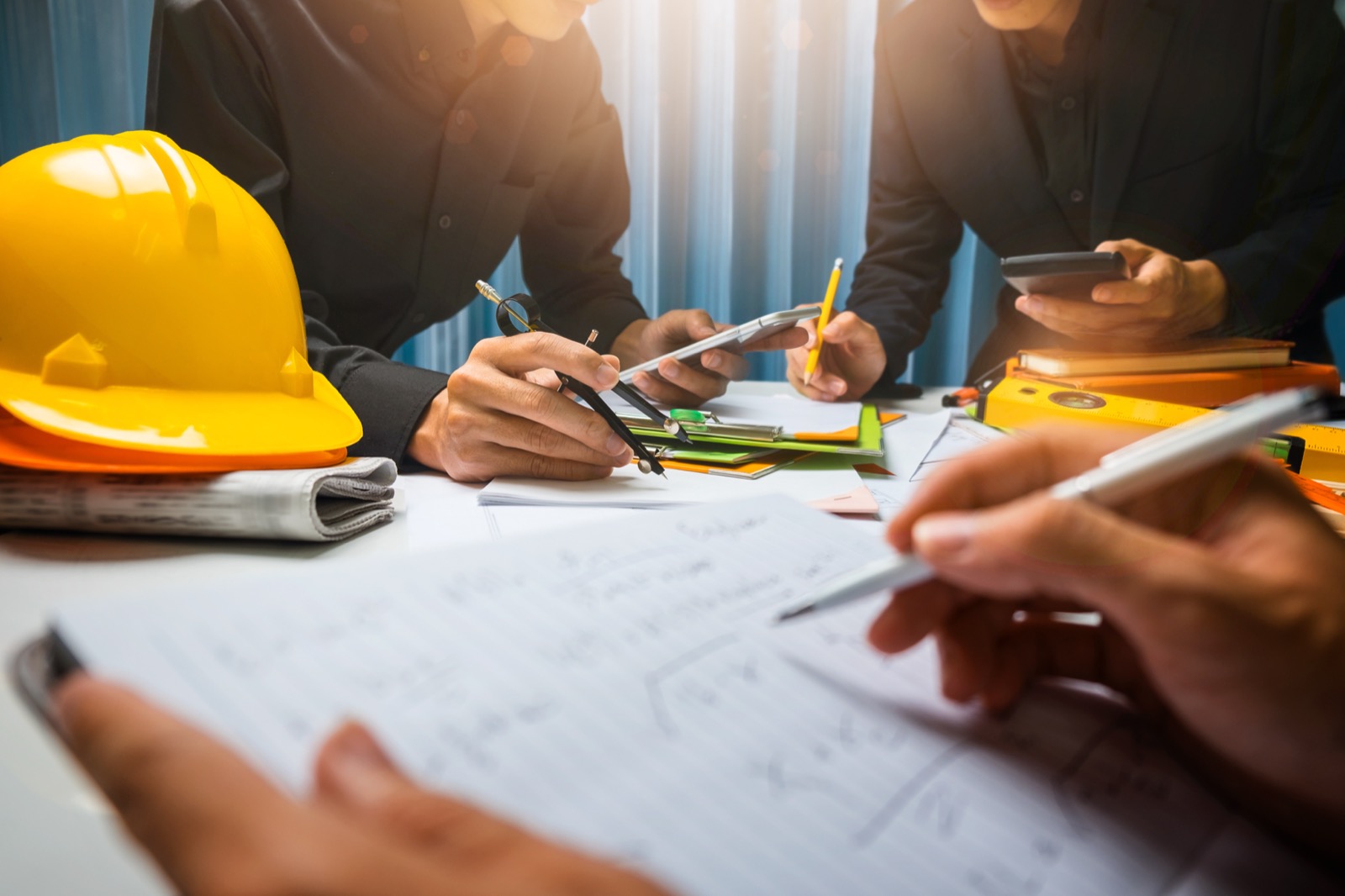 A project team reviewing drawings at a table beside a hard hat