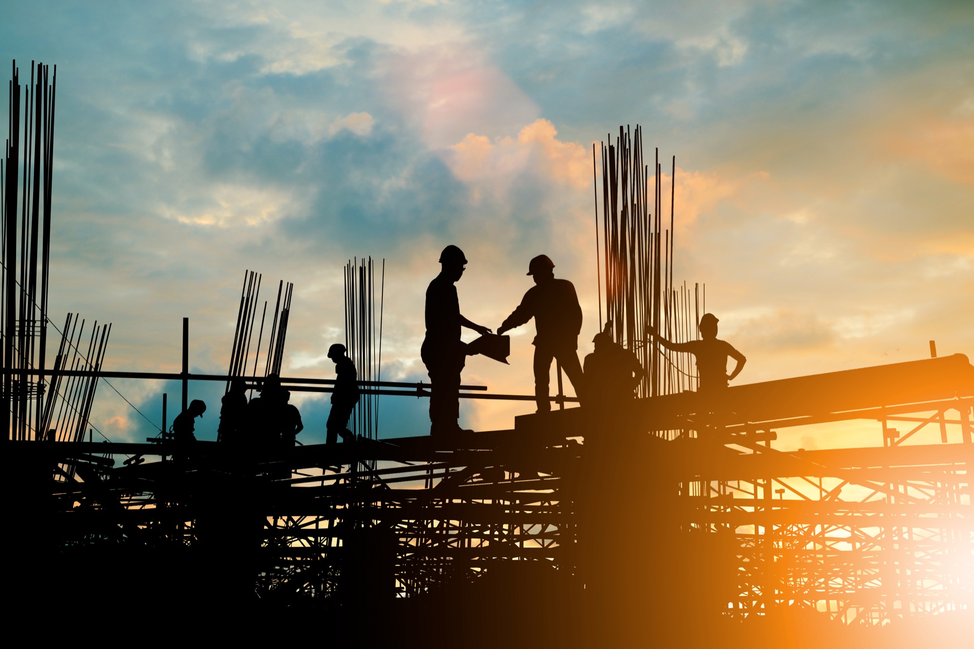 A crew on a steel frame at sunset