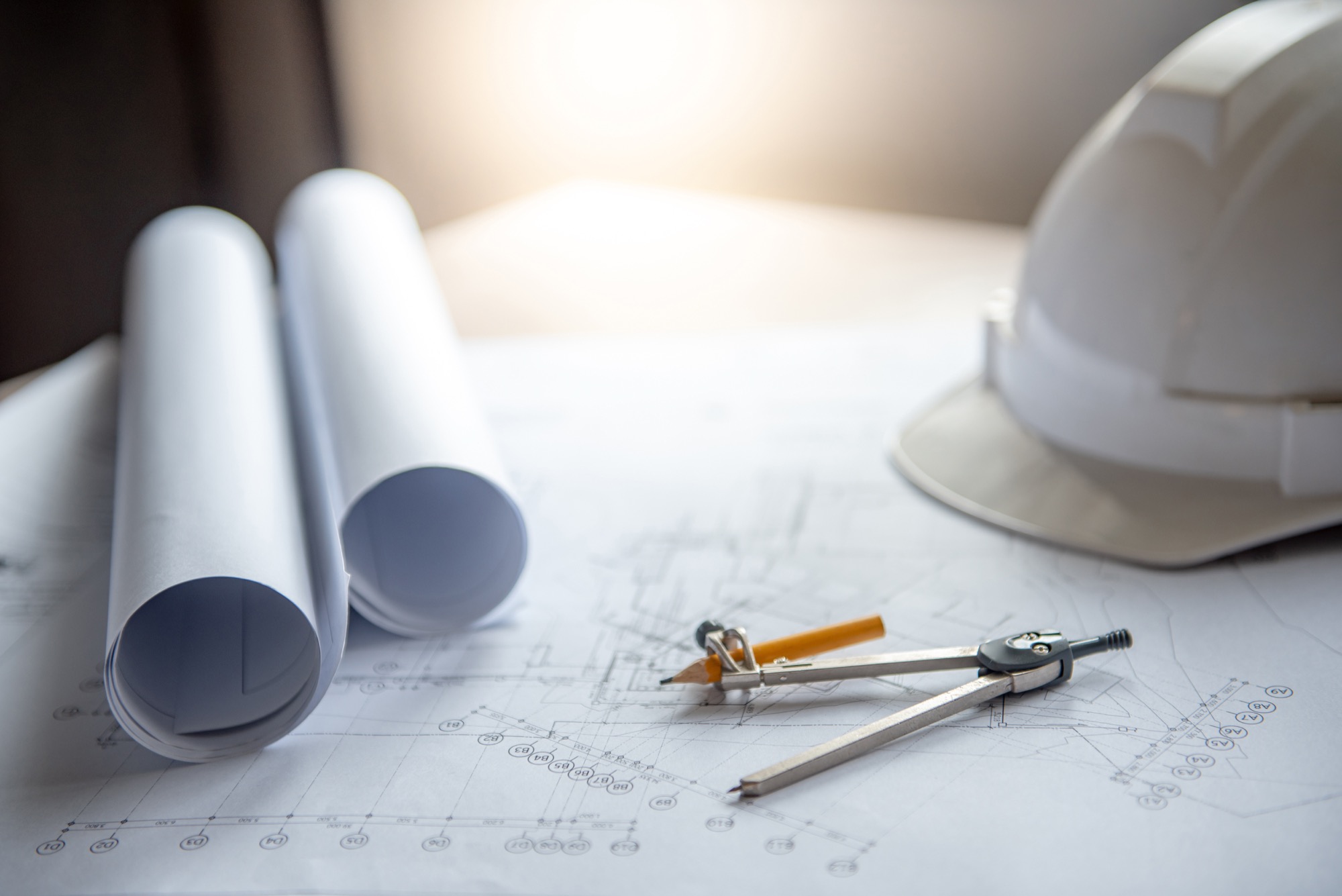 Rolled drawings, a compass and a hard hat on a desk