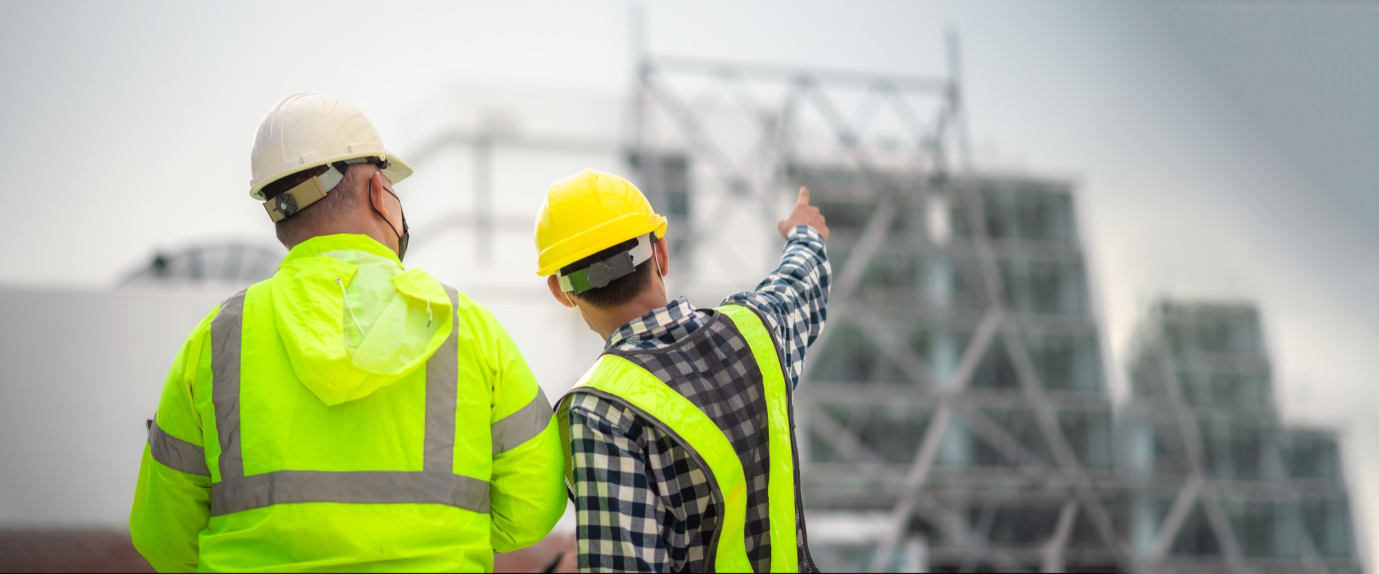 Two site managers in hard hats looking over a steel structure